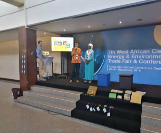 Three speakers on stage at the 7th West African Clean Energy and Environment Trade Fair presenting to an audience